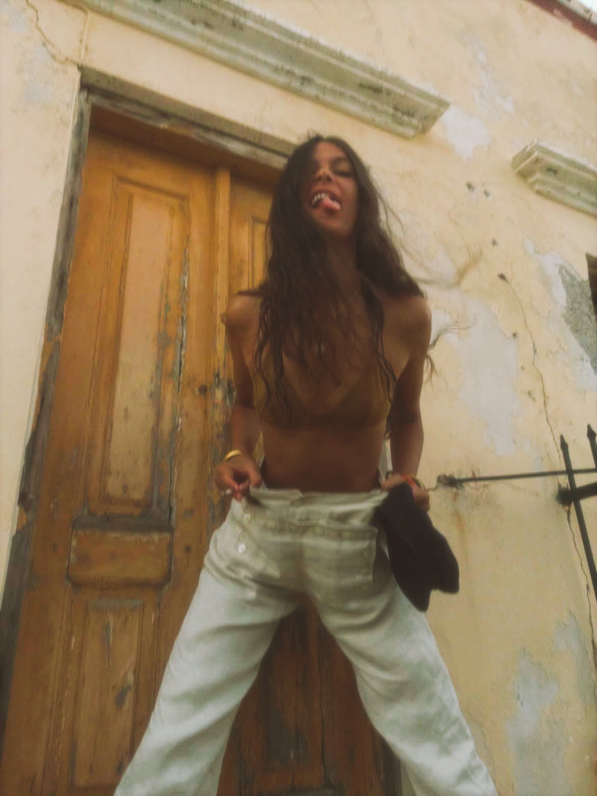 White 13 Buttons sailor trousers worn in front of a weathered door